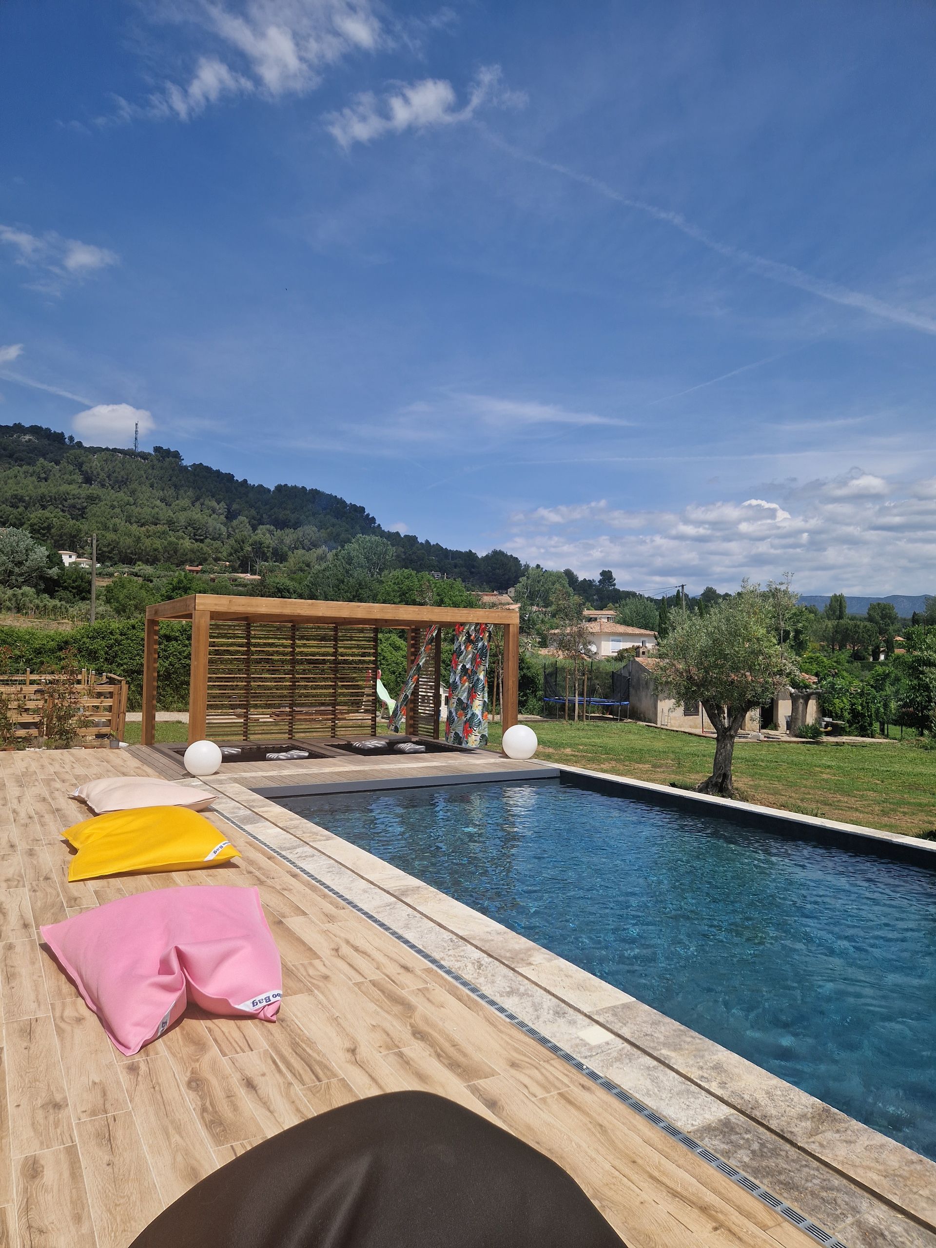Photo d'une piscine avec deux poufs (rose et jaune) sur le bord
