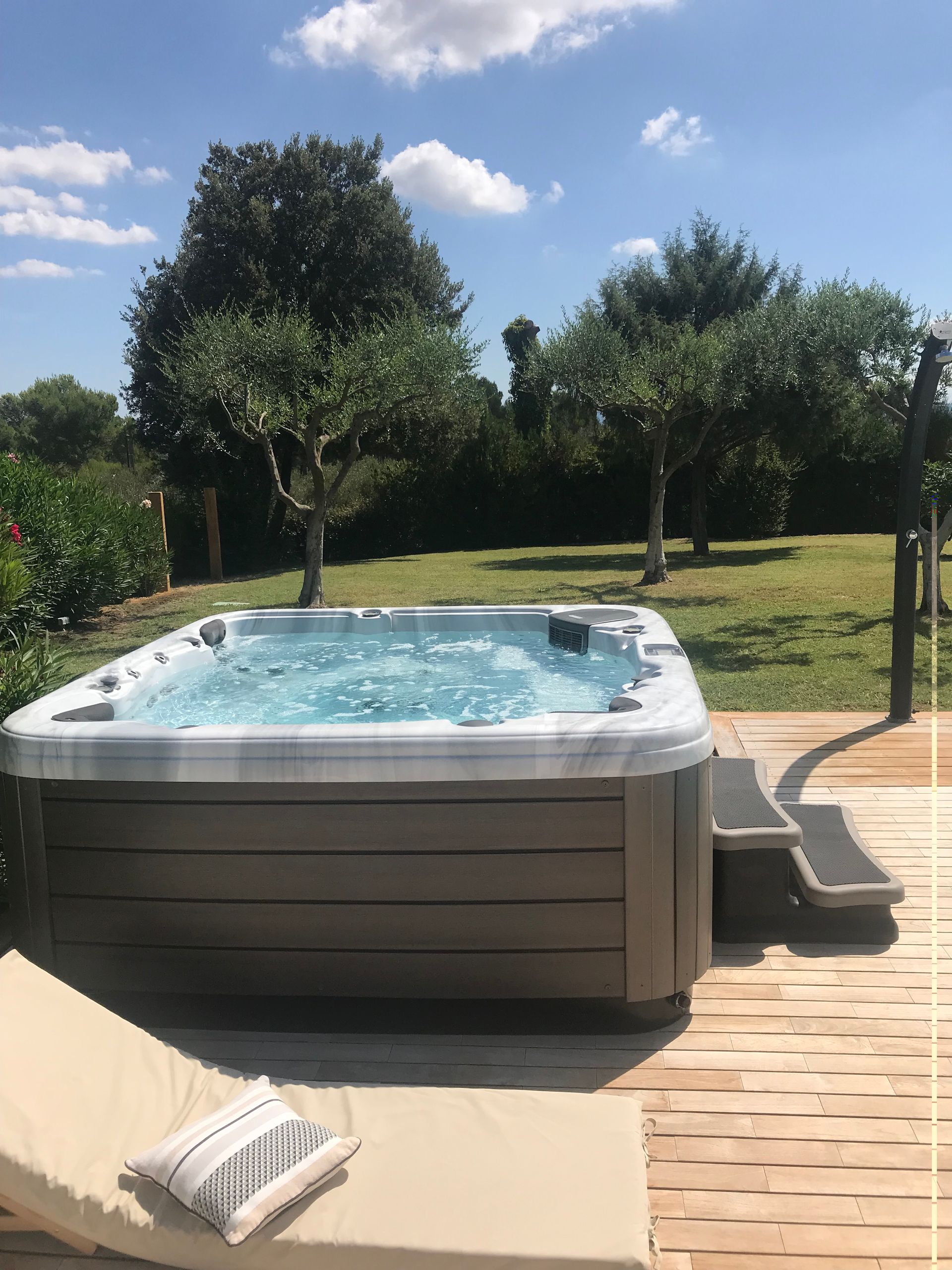 Photo d'un spa marron sur une terrasse avec un transat