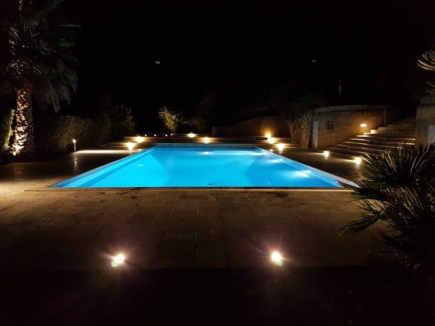 Photo d'une piscine prise de nuit avec éclairage intérieur et extérieur