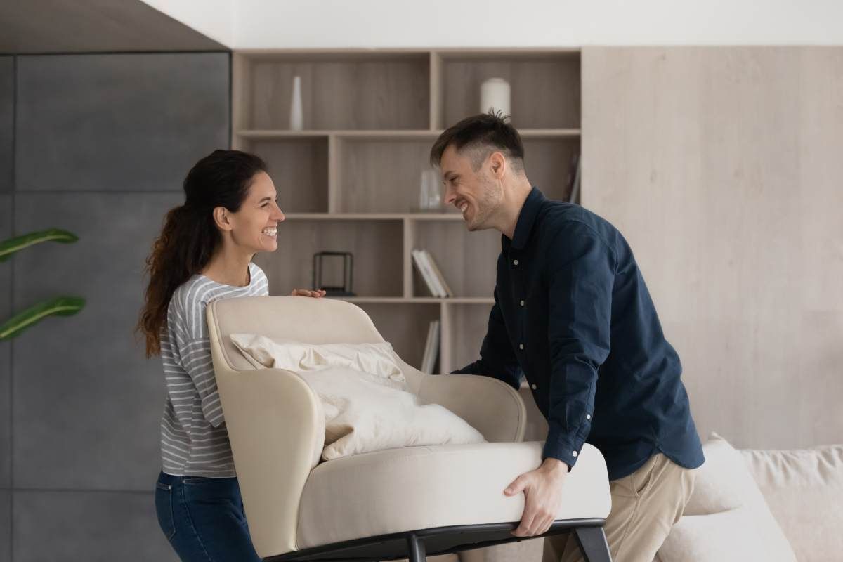 Ein Mann und eine Frau schieben einen Stuhl in ein Wohnzimmer.