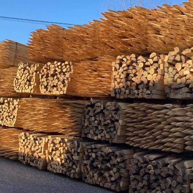Pilas de postes de cerca de madera de diferentes tamaños, al aire libre.