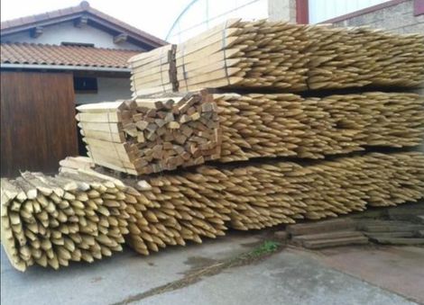 Camión cargado con pilas de tablones de madera, asegurados con correas azules, al aire libre.