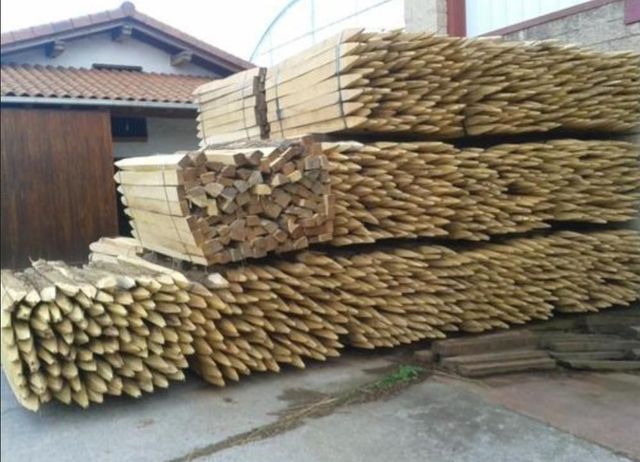 Camión cargado con pilas de tablones de madera, asegurados con correas azules, al aire libre.