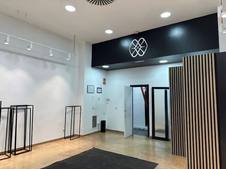 Vista interior de una tienda de ropa vacía con paredes y estantes de exhibición en blanco y negro.