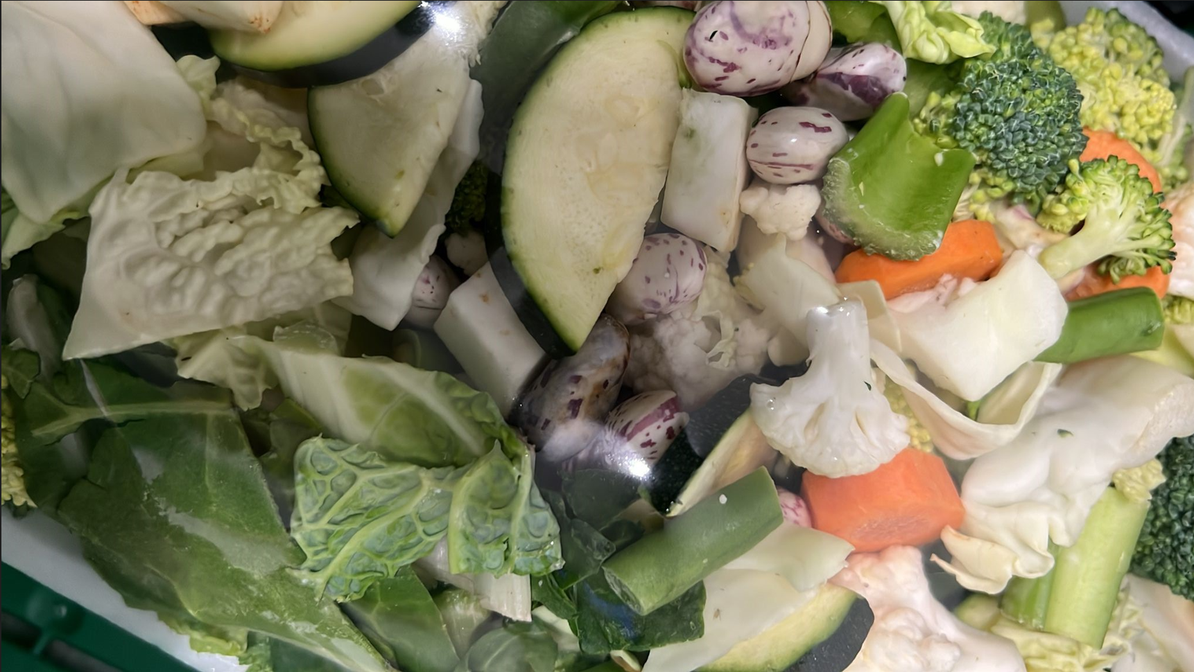 Eine Nahaufnahme eines Tellers mit Gemüse und einem Löffel darin.