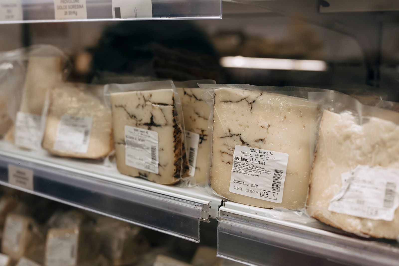 Ein Regal voller Käse in Plastiktüten mit vielen verschiedenen Sorten.
