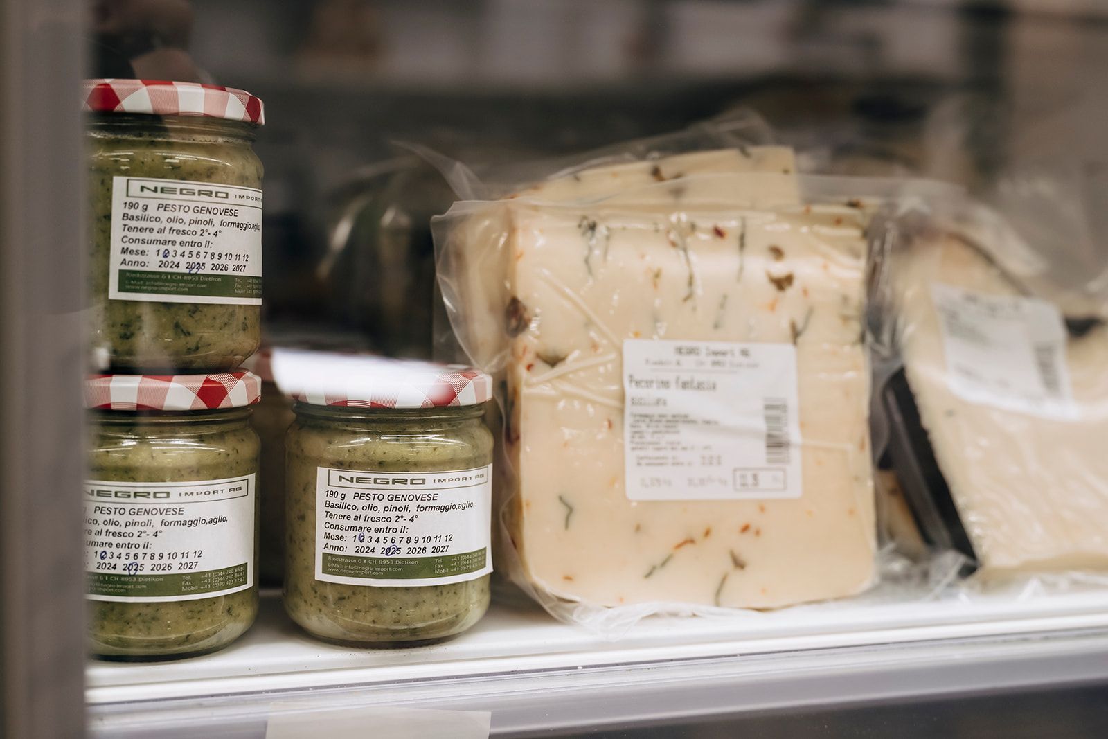 Ein Regal voller Pestogläser und Käsescheiben.