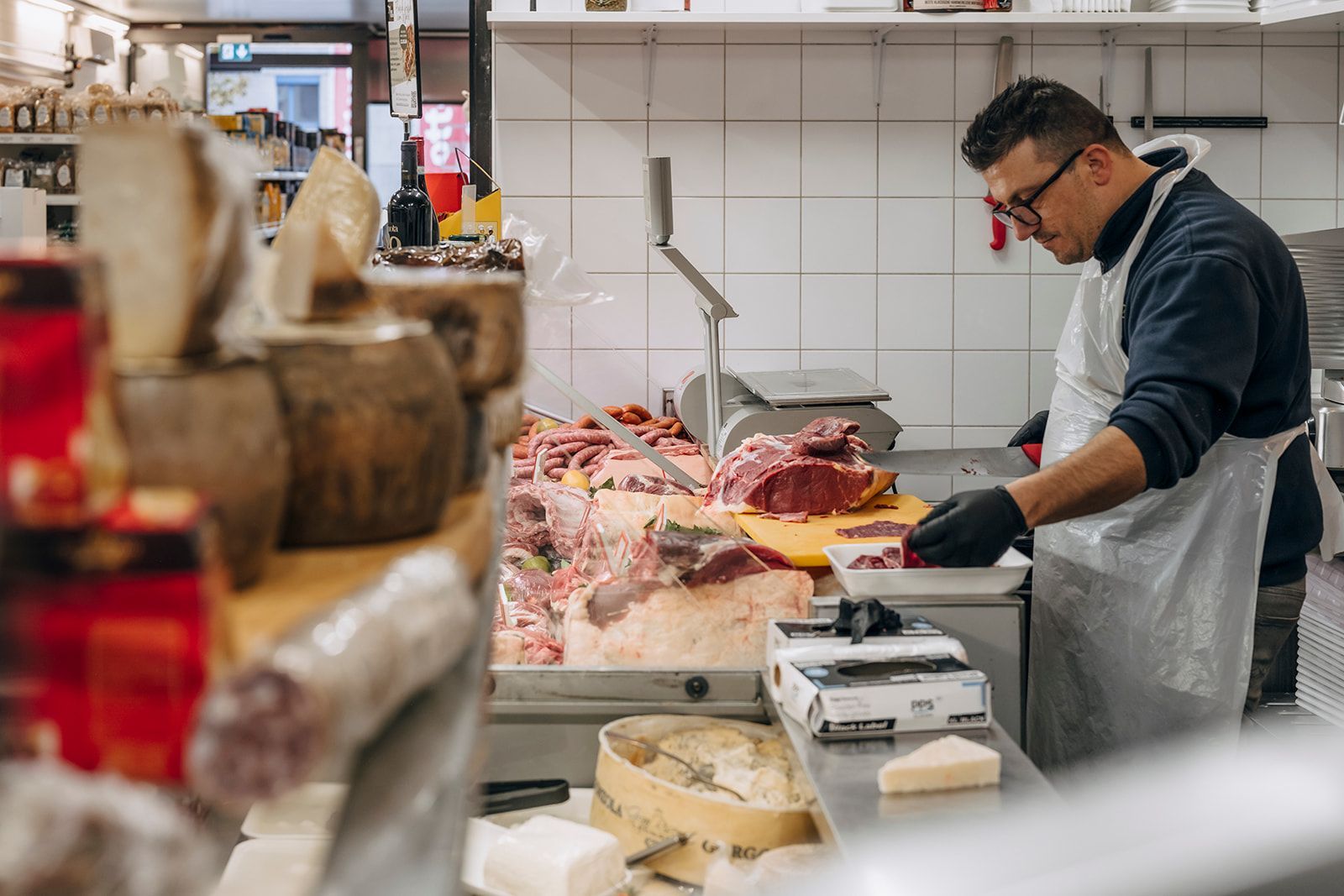 Ein Mann schneidet in einer Küche Fleisch auf einem Schneidebrett.