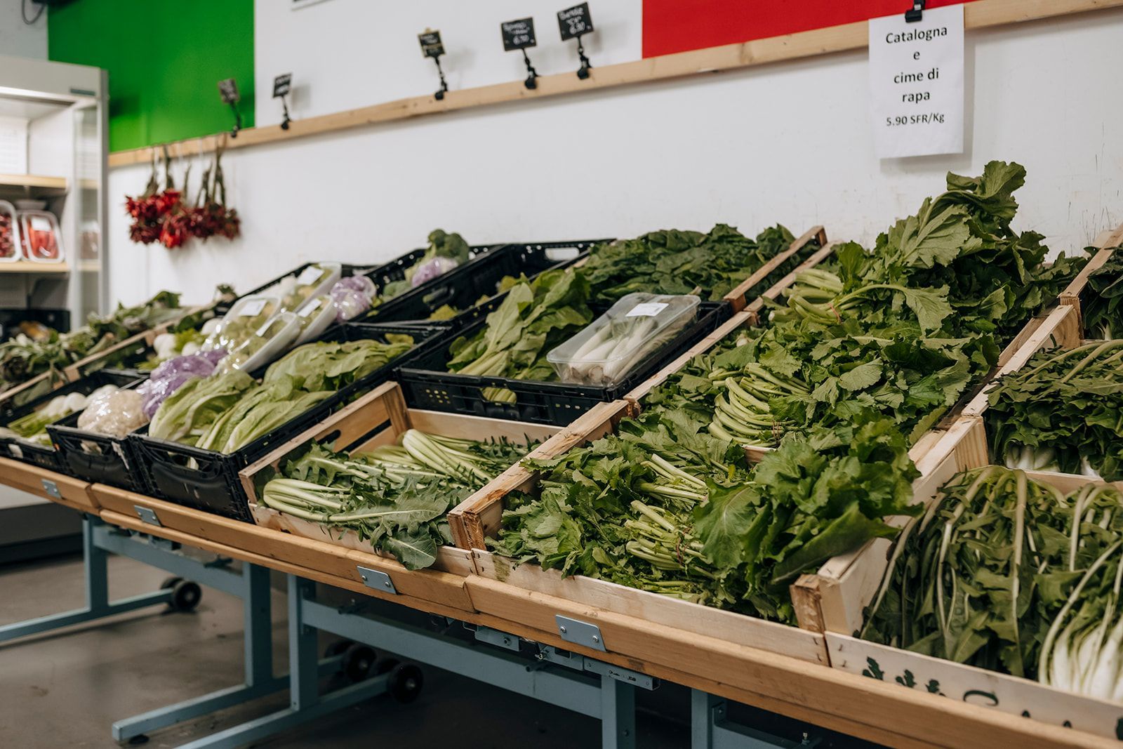 In einem Lebensmittelgeschäft werden auf einem Holztisch verschiedene Gemüsesorten ausgestellt.