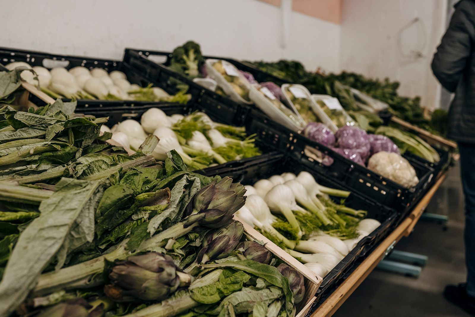 Eine Person steht vor einem Tisch voller Gemüse.