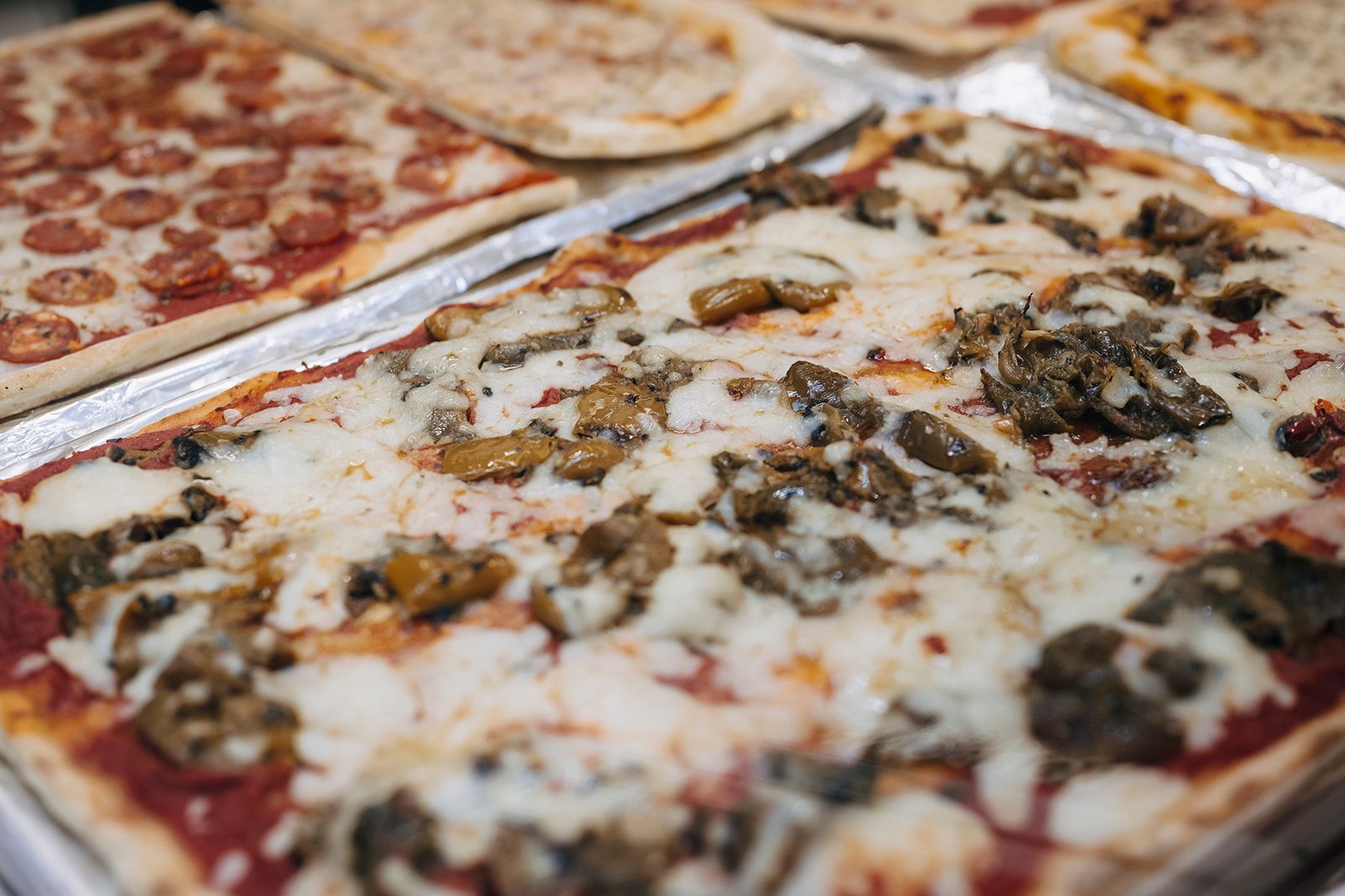 Auf dem Tisch stehen viele verschiedene Pizzasorten.