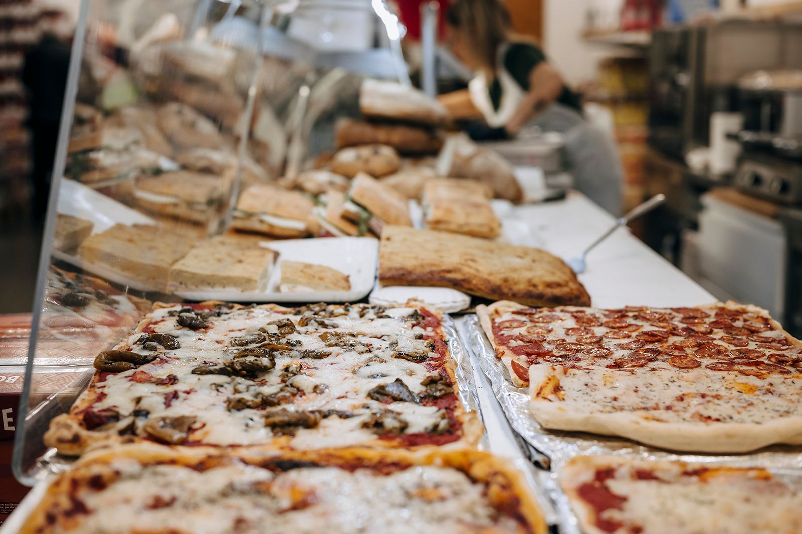 Auf der Theke einer Bäckerei liegen verschiedene Pizzen.