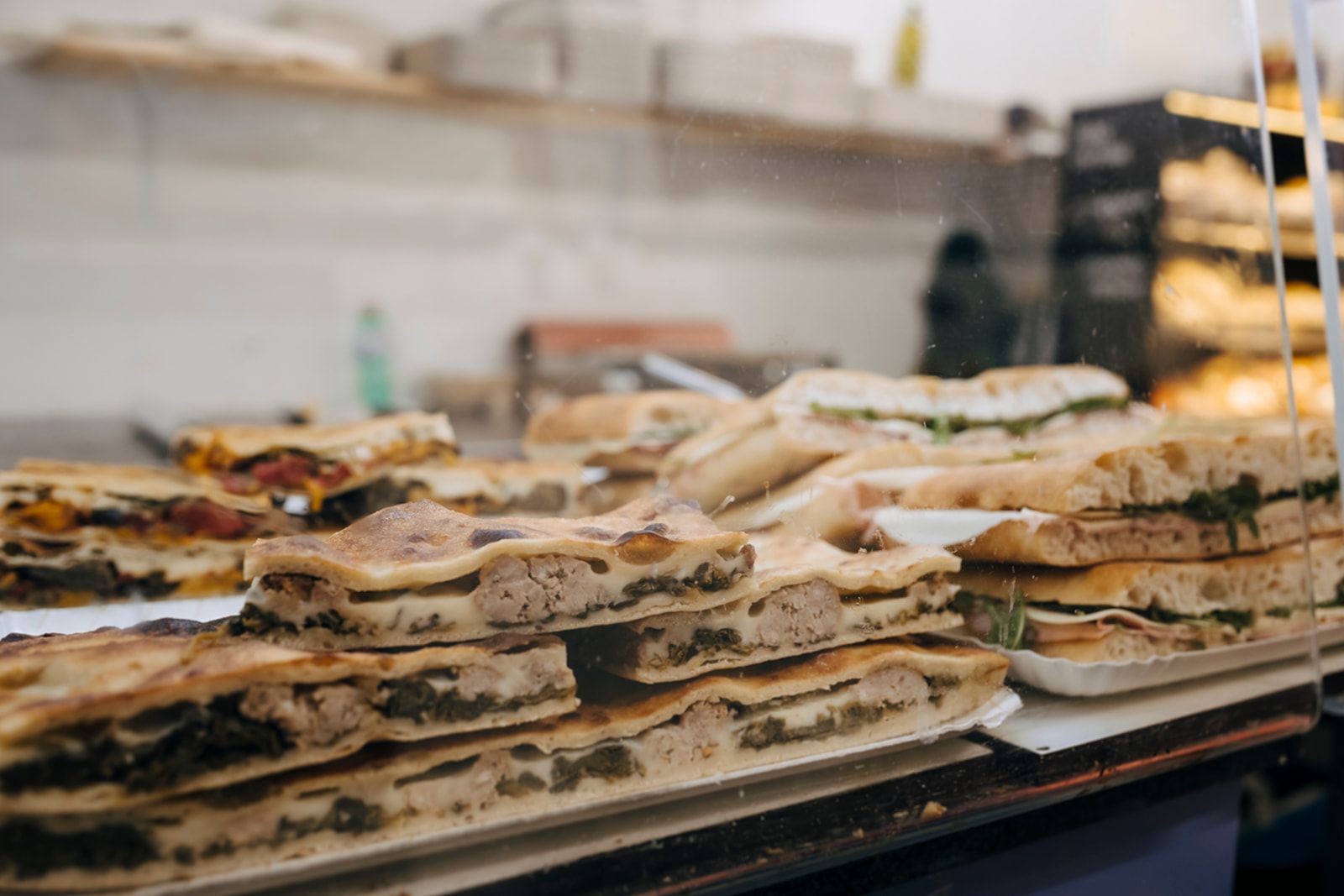 In einer Bäckerei sind auf einem Tisch mehrere Sandwiches übereinander gestapelt.