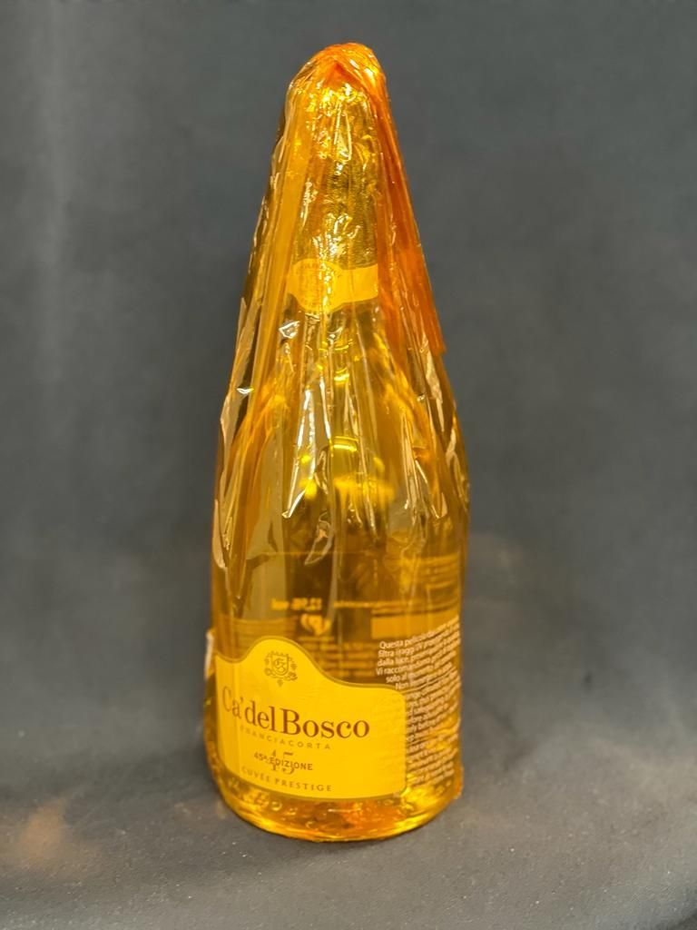 Eine Flasche Champagner ist in Plastik eingewickelt und steht auf einem Tisch.