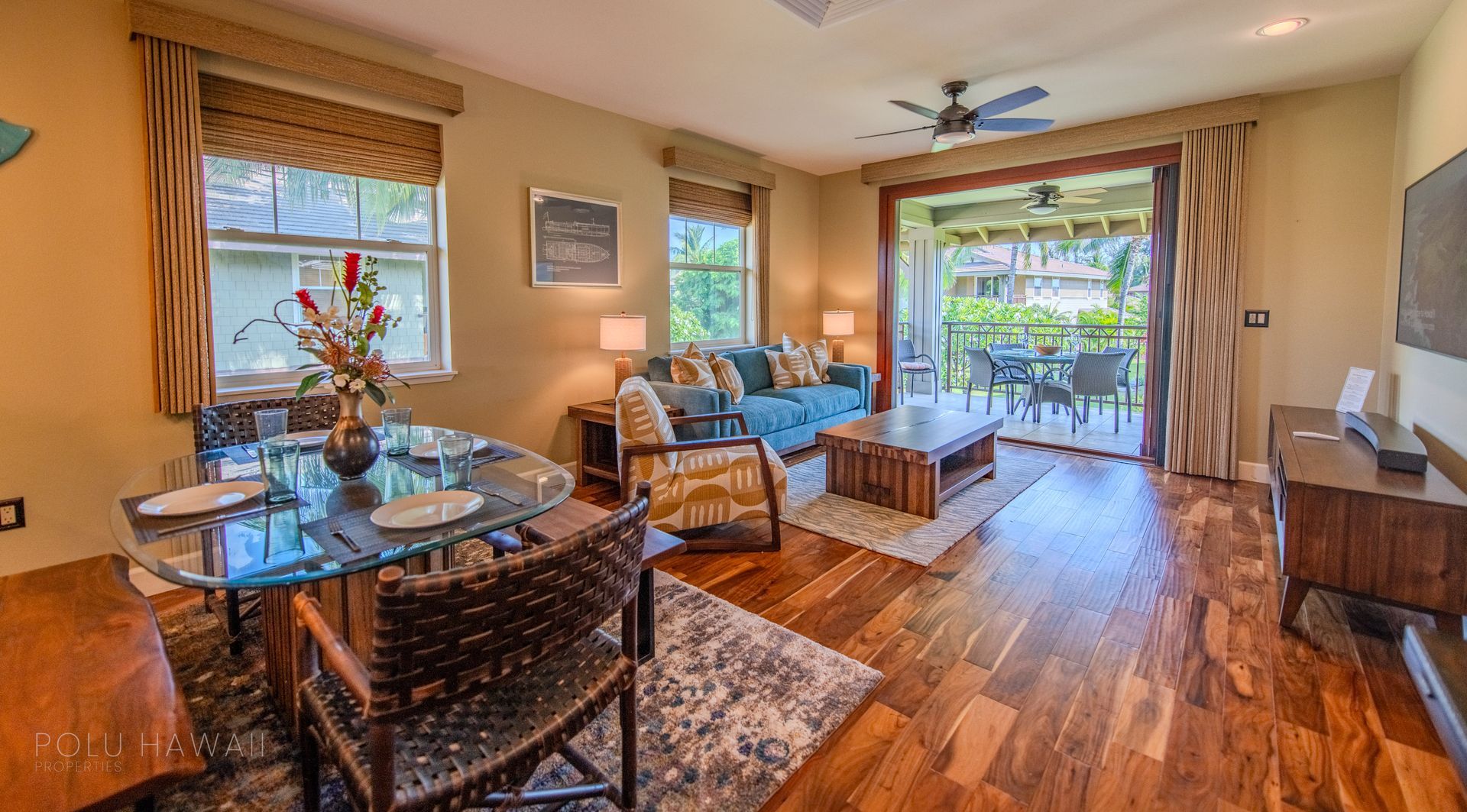 A living room with a couch , table , chairs and a ceiling fan.