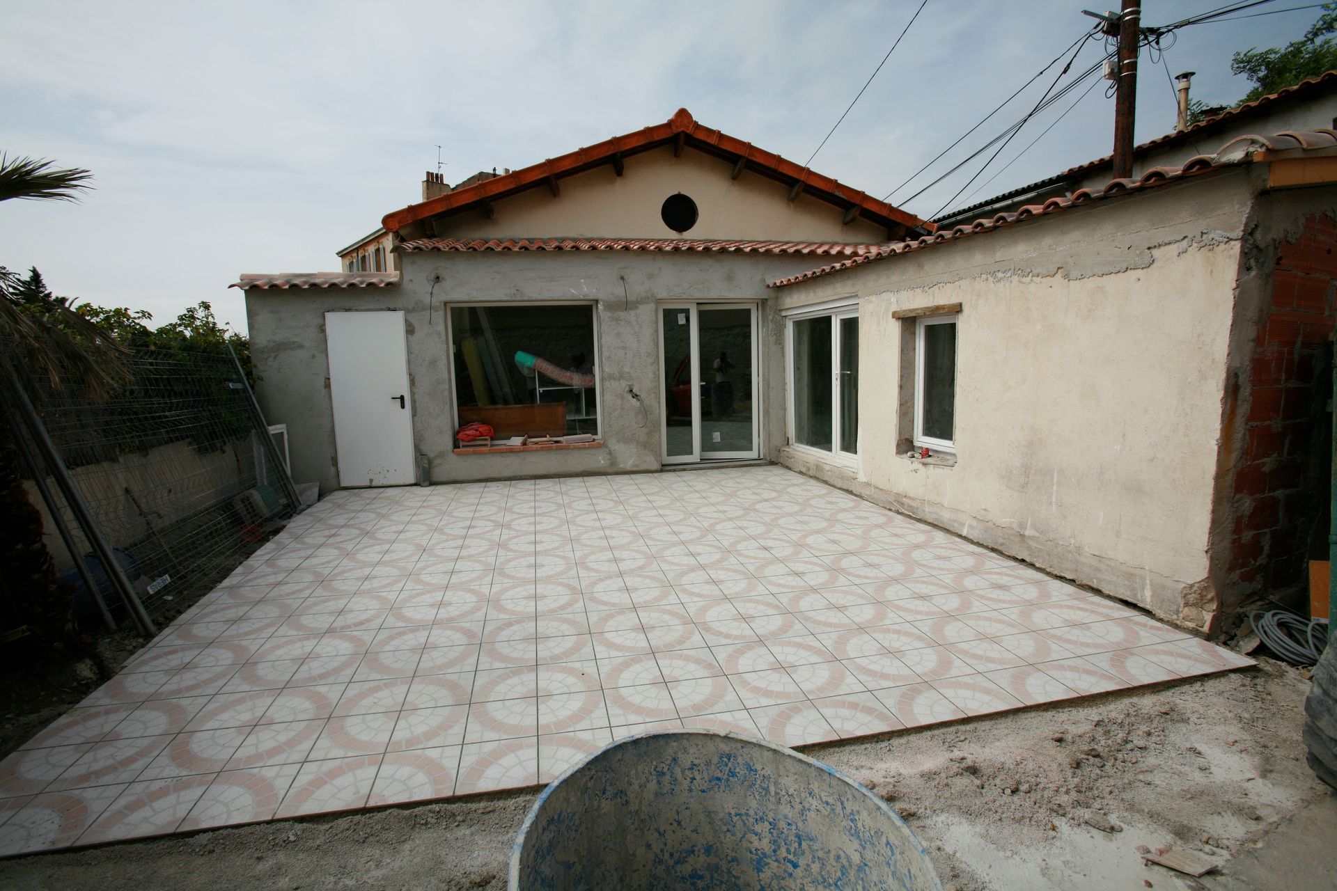 Cour carrelée vide avec une petite maison et des portes coulissantes en verre à l'arrière.