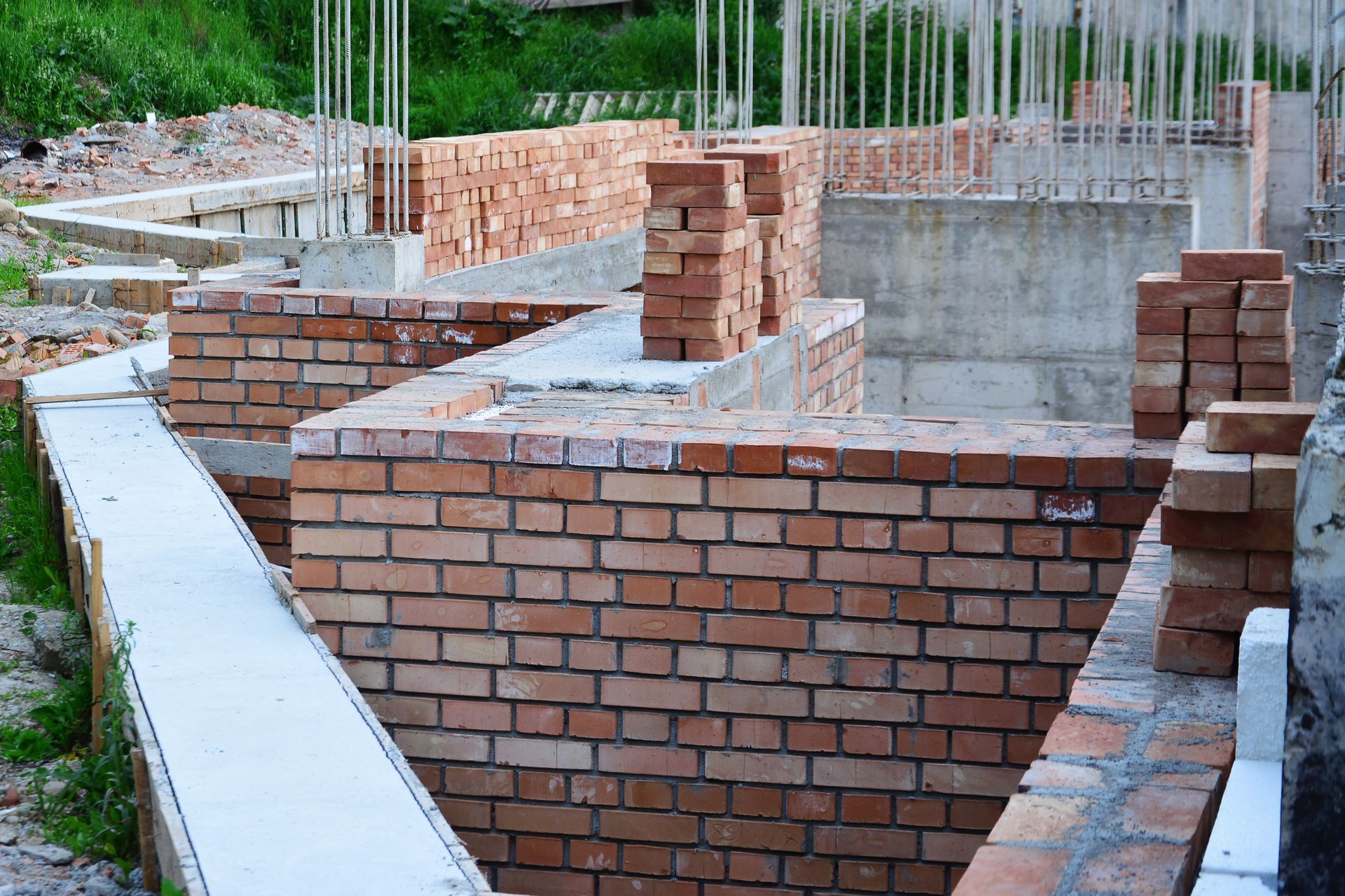 Fondations en briques partiellement construites avec semelles en béton et armatures verticales sur un chantier de construction