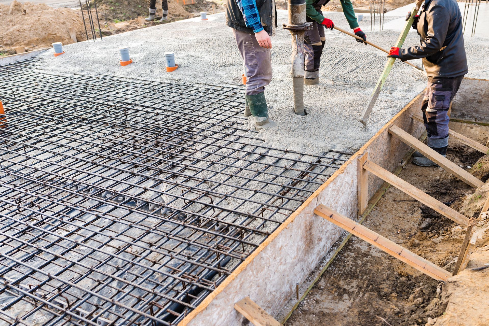 Des ouvriers coulent du béton sur des armatures en acier sur un chantier de construction