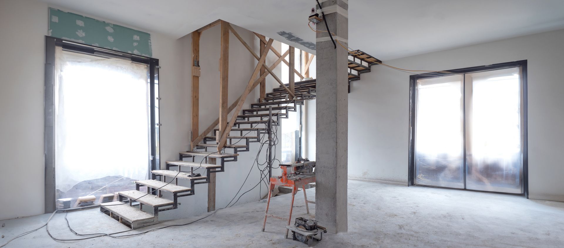 Intérieur inachevé avec un escalier flottant et de grandes fenêtres donnant sur un paysage enneigé