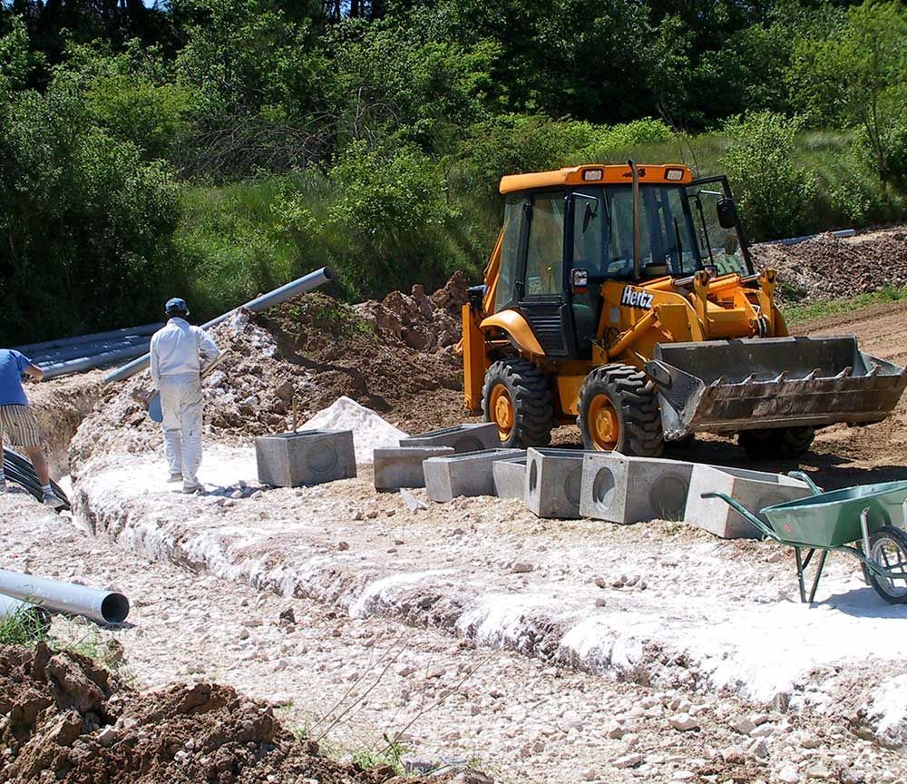 Une pelleteuse et des ouvriers construisent un mur en béton sur un chantier boueux