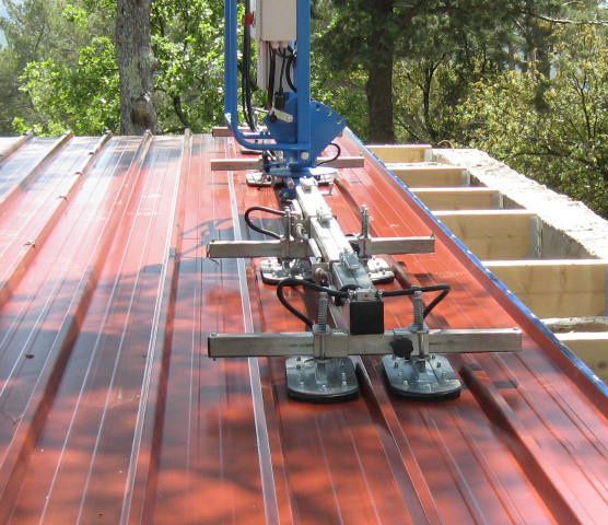 Installation de panneaux solaires sur le toit d'une toiture métallique rouge à l'aide d'outils de fixation par ventouses.