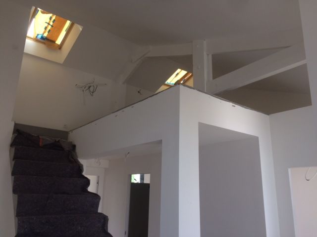 Intérieur avec murs blancs, escalier sombre, fenêtres de toit et étage supérieur de style loft