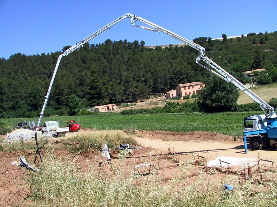 Camions-pompes à béton coulant les fondations d'un chantier de construction en zone rurale