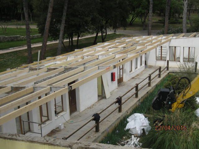 Bâtiment modulaire blanc partiellement construit, avec poutres de toit apparentes et matériaux de construction extérieurs