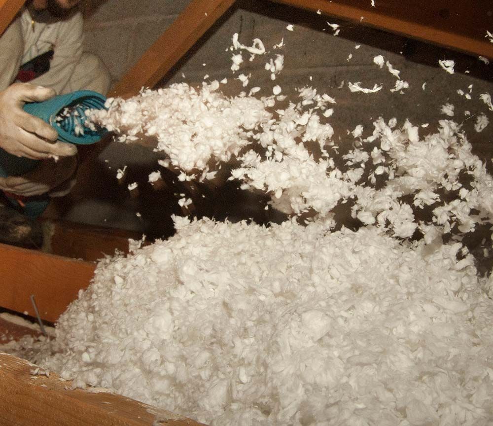 Remplissage manuel d'une peluche avec du rembourrage blanc, au-dessus d'une table recouverte de fibres de polyester.