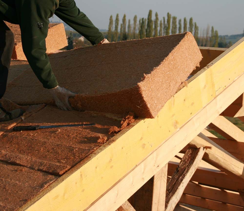 Ouvrier installant des bardeaux bruns sur une charpente de toit en pente