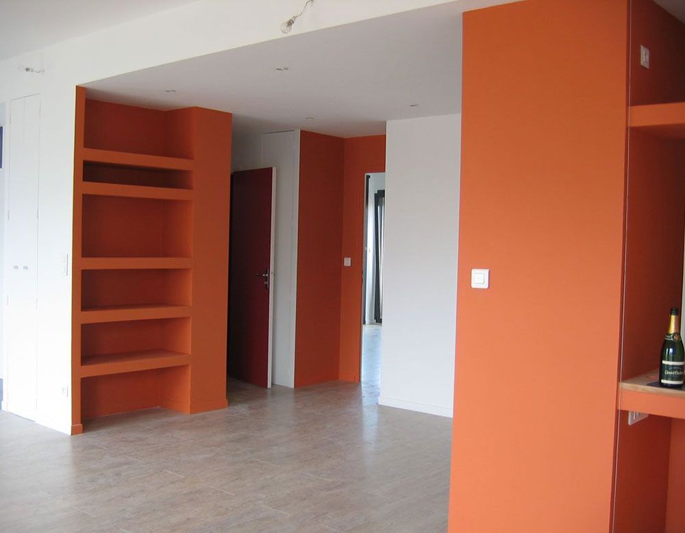 Pièce vide aux murs orange, étagères intégrées et sol gris