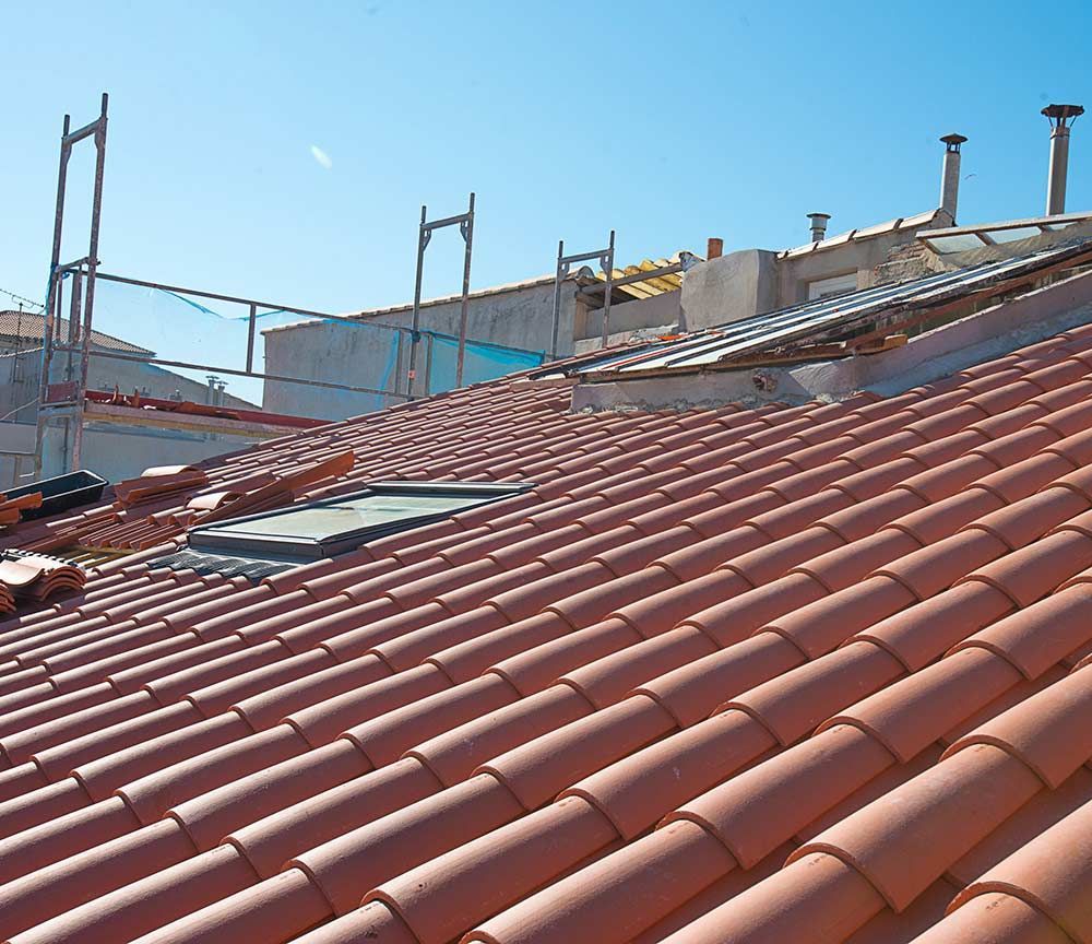 Toits de tuiles rouges sous un ciel bleu clair, avec des structures et des antennes en arrière-plan