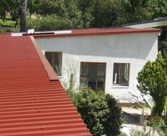 Maison blanche au toit rouge, entourée d'arbres, vue d'en haut