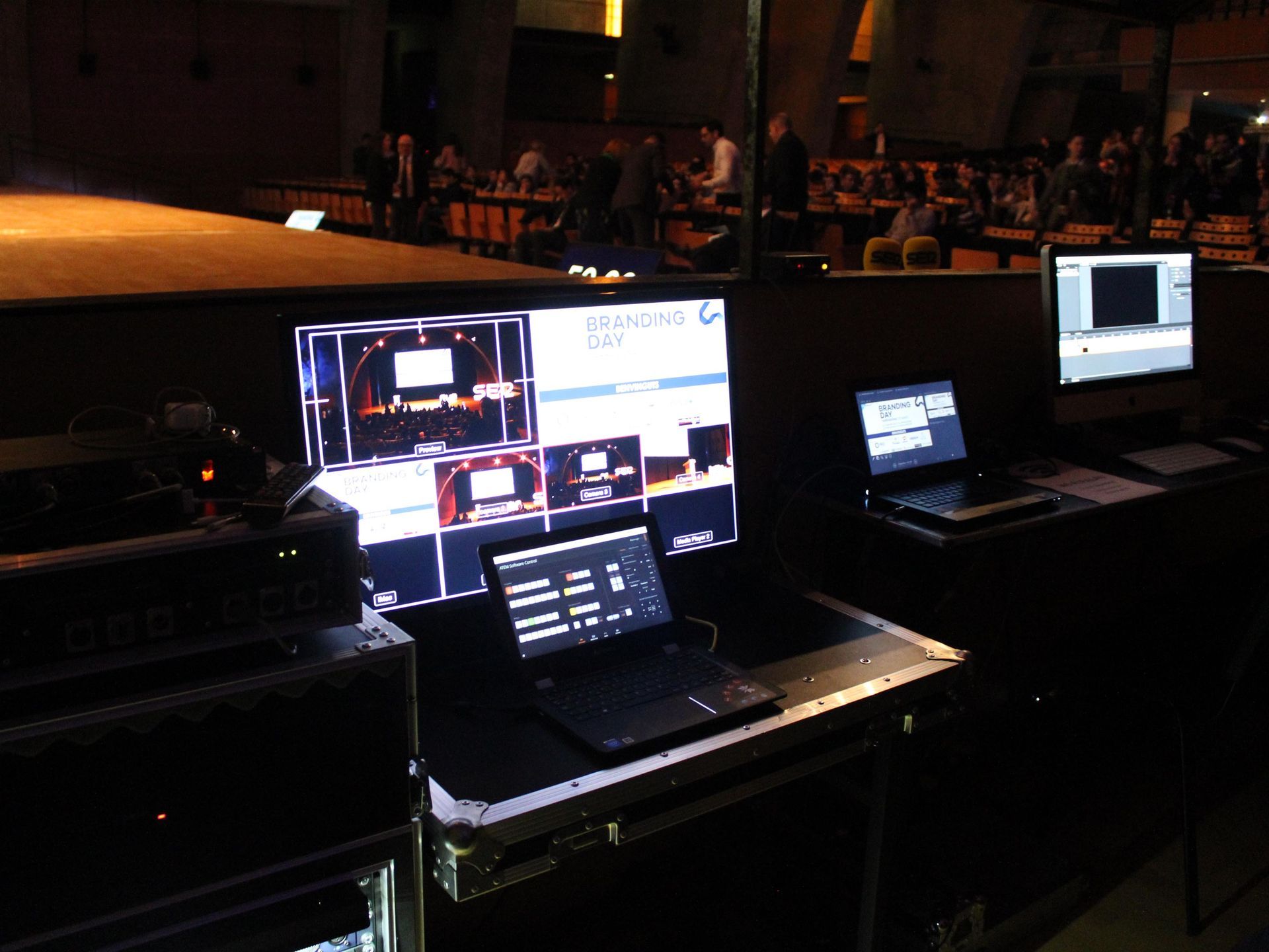 Dos monitores y una computadora portátil están sobre una mesa en una habitación oscura.