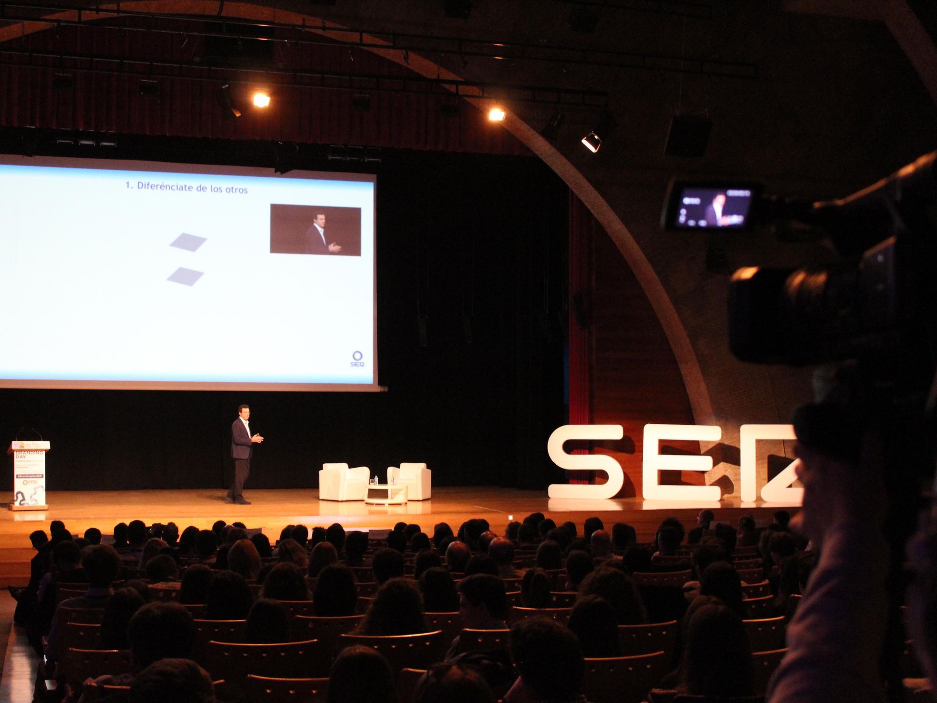 Un hombre está dando una presentación frente a una pantalla grande que dice sec