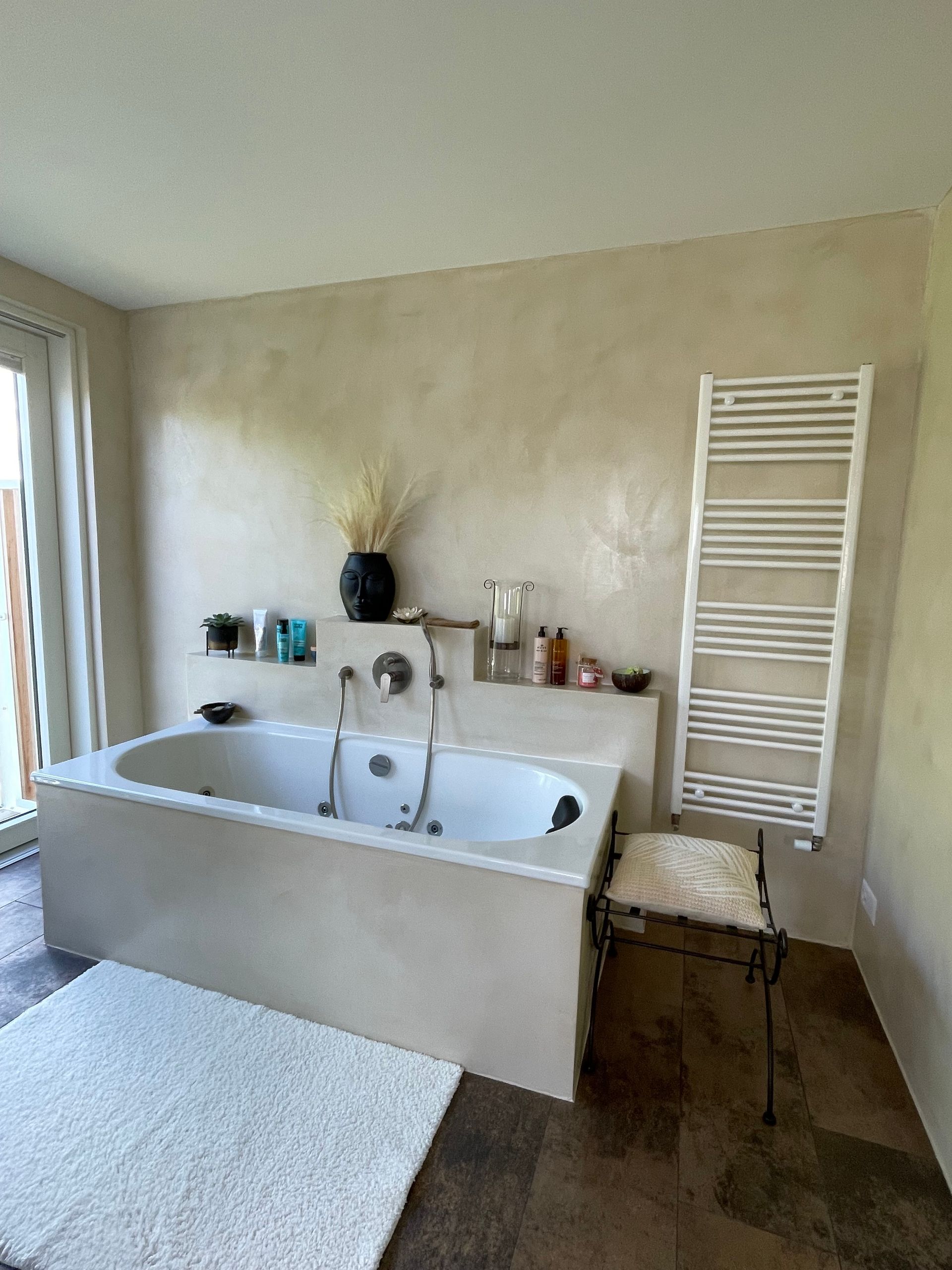 Immeuble d'appartements beige à plusieurs étages avec balcons, situé sur une pelouse verdoyante sous un ciel bleu azur.