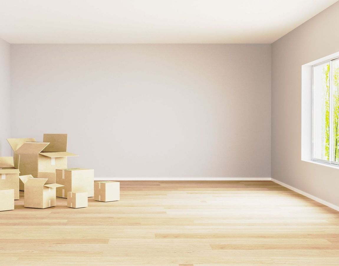 Una habitación vacía con cajas en el suelo y una ventana.