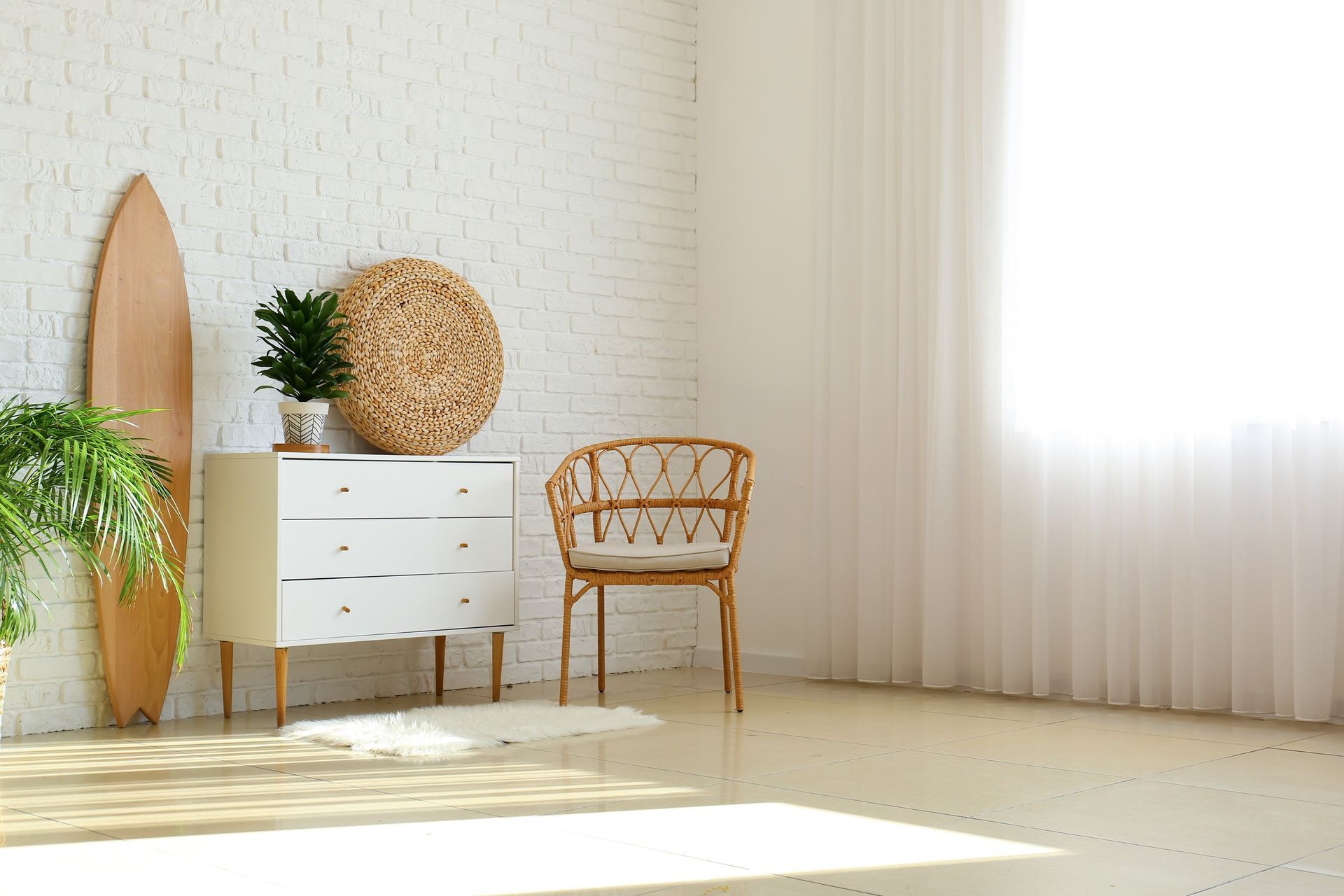 Una habitación vacía con una cómoda, una silla, una tabla de surf y plantas.