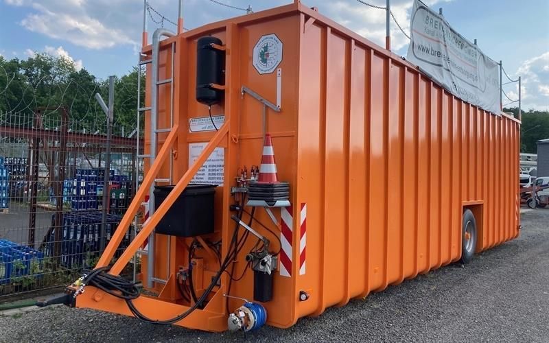 Ein großer orangefarbener LKW steht auf einem Parkplatz