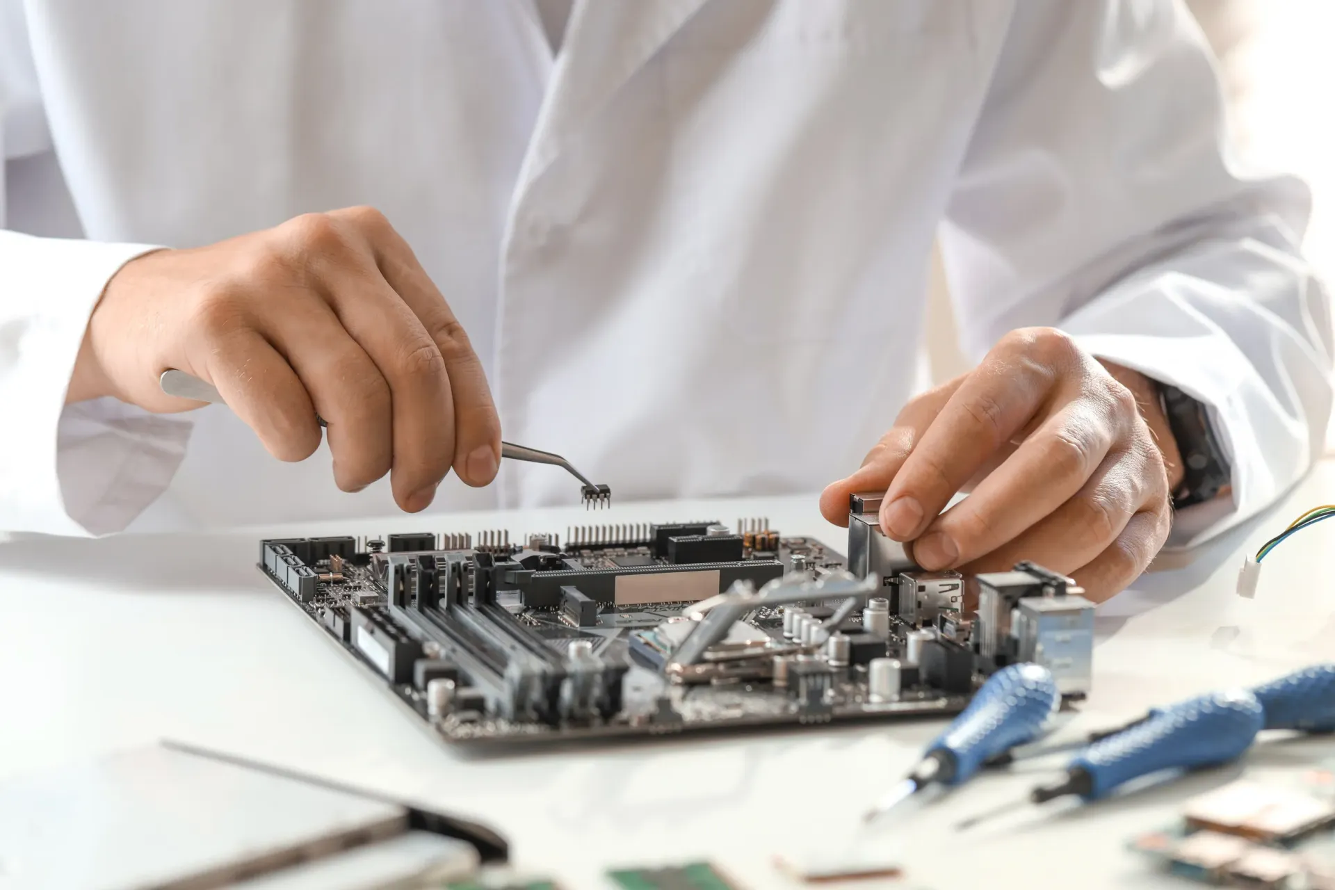 Un hombre con una bata de laboratorio está trabajando en una placa base.