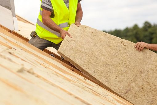 Des ouvriers installent des panneaux d'isolation sur un toit en construction