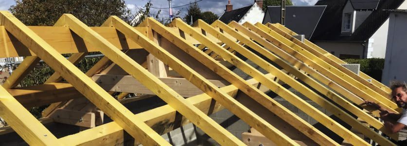 Des fermes de toit en bois sont installées sur une maison en construction.