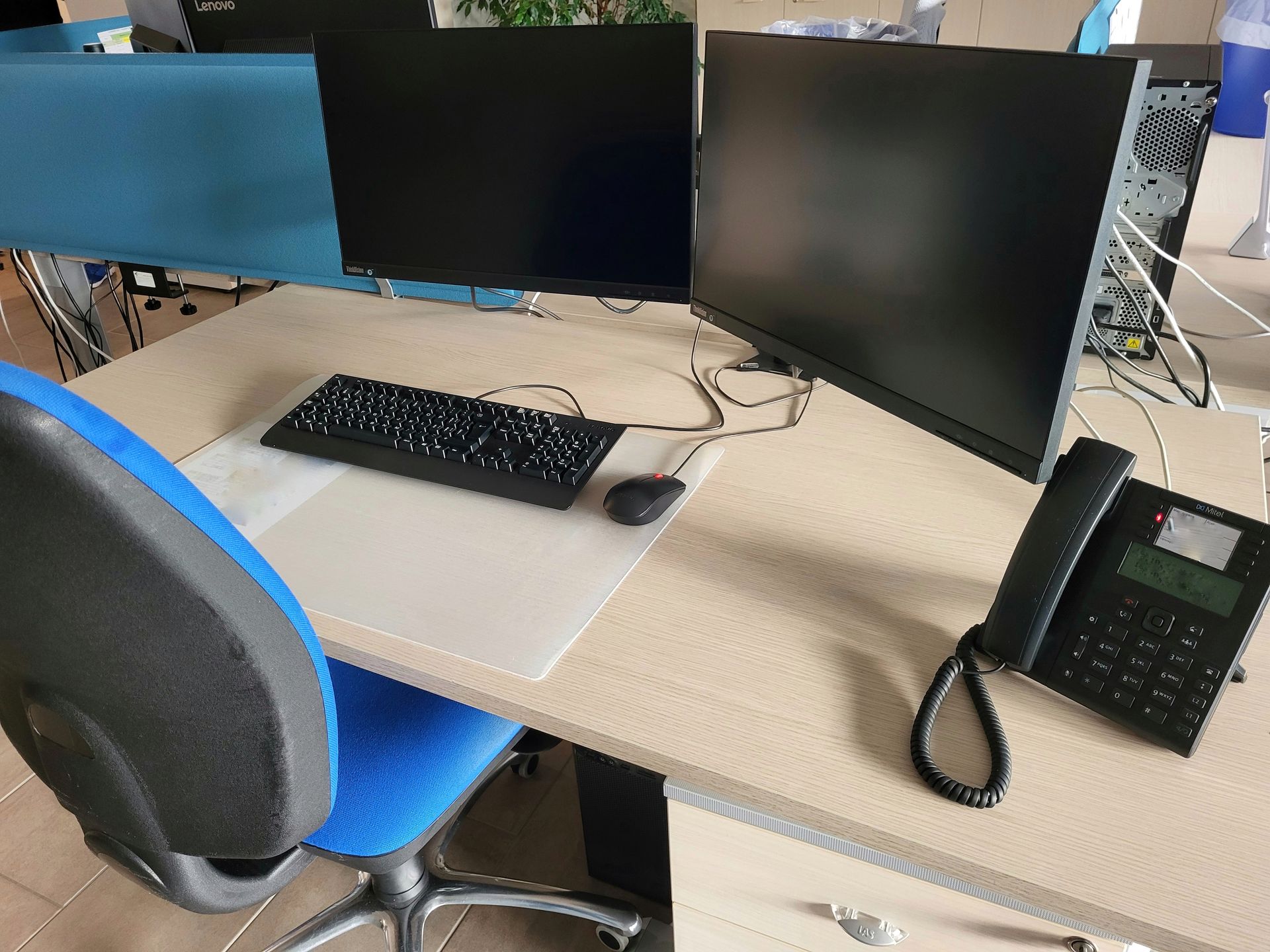 Un bureau propre avec deux écrans et un téléphone dessus