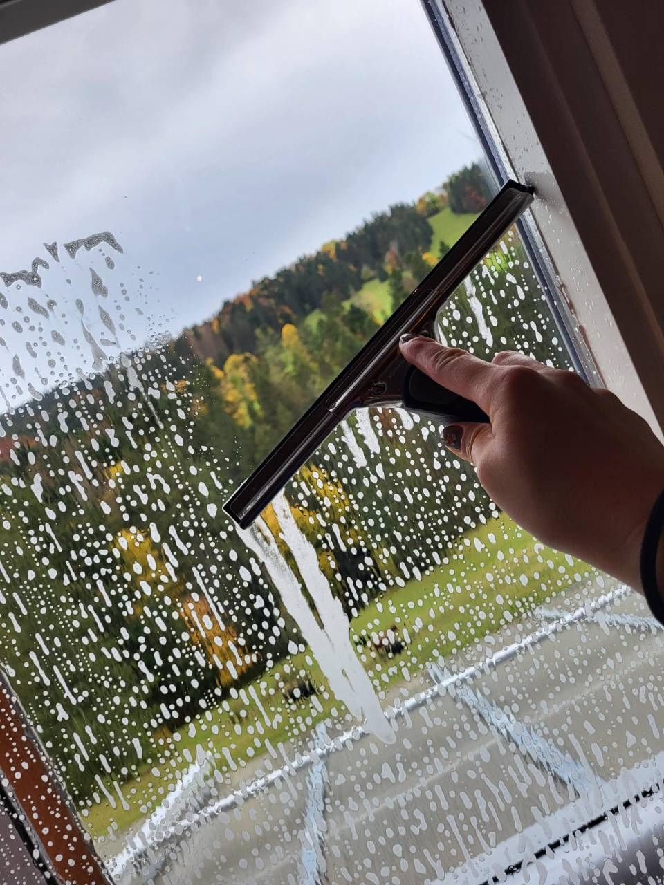 Une personne nettoie une fenêtre avec une raclette