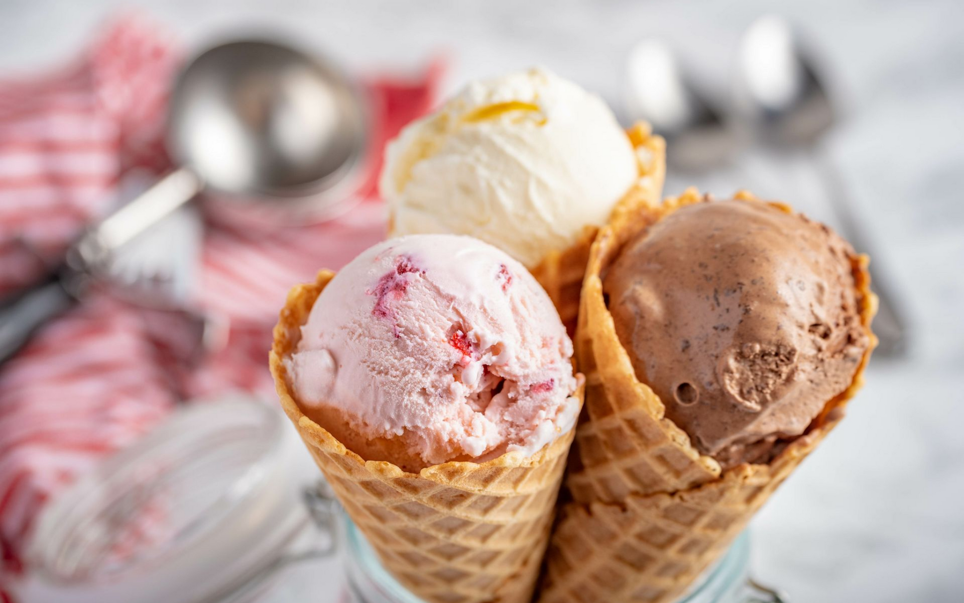 Trois cornets de glace : fraise, vanille et chocolat. Servis dans des cornets gaufrés.