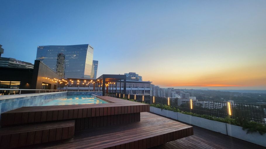 Sandton Accommodation The Lineal Rooftop pool with city view at dusk; modern buildings and sunset sky.