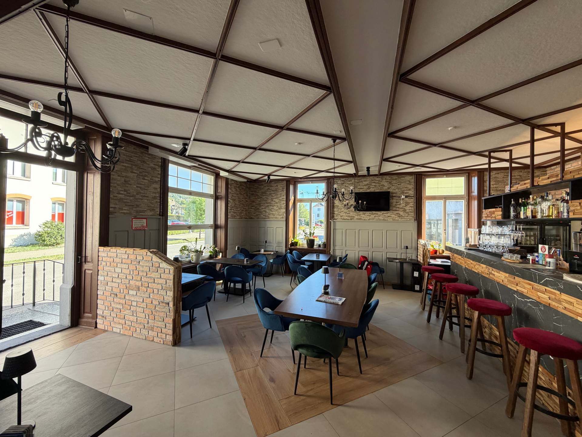Restaurant mit offenem Aussenbereich, blauen Stühlen, Holztischen und einer Bartheke