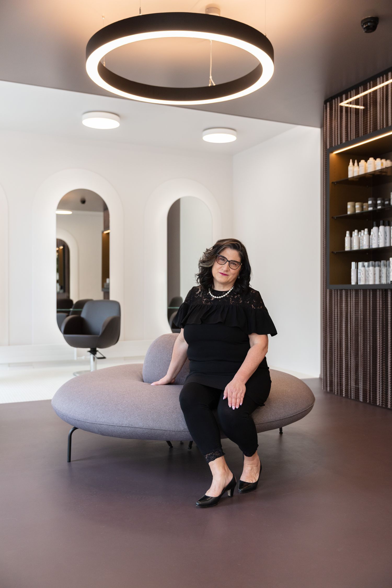 Eine Frau sitzt auf einer Couch in einem Salon.