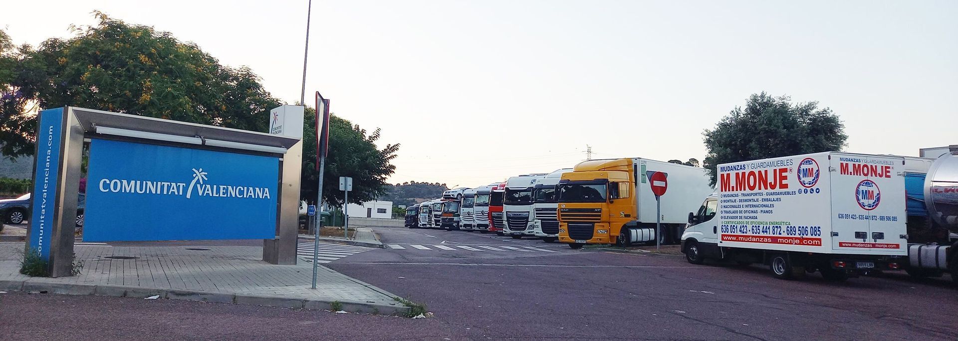 Hay muchos camiones estacionados frente a un cartel azul.