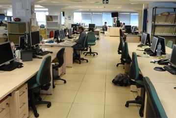 Una oficina grande con muchos escritorios y sillas.